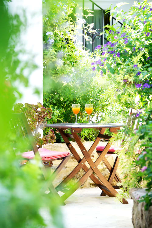 Soleado patio de jardín en La Vista Medina Stays con mesa de madera, bebidas frescas y flores vibrantes en Medina Sidonia