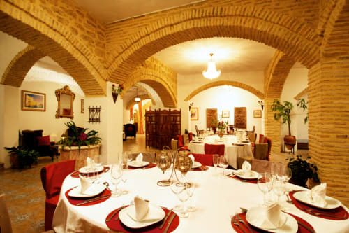 Elegante comedor de La Vista Medina Stays con arcos de ladrillo, mesas redondas con servilletas rojas y manteles blancos en Medina