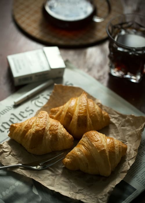 Cornetti appena sfornati con caffè e giornale al tavolo colazione di Casanova Hideaway Venezia