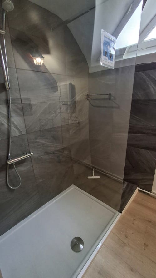 Modern walk-in shower with dark tile walls and glass enclosure at Les Gîtes de l'Impériale B&B in Sermizelles, France