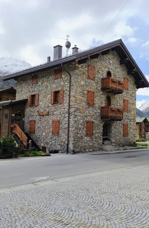 Esterno dell'hotel Al Dos a Livigno - edificio in pietra con balconate in legno e vista sulle montagne