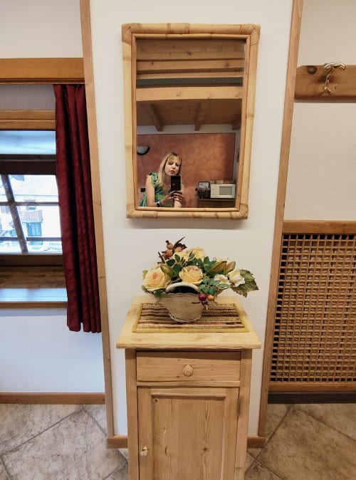 Area vanity della camera studio presso l'hotel Al Dos a Livigno con specchio in legno, mobile lavabo e fresco bouquet floreale