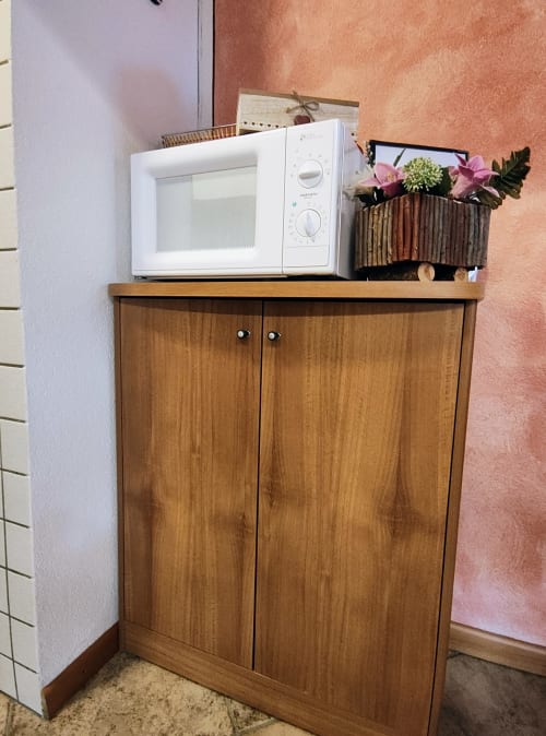Angolo cucina della suite presso Al Dos Livigno con mobile in legno, microonde e fiori decorativi