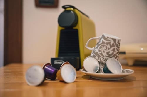Macchina da caffè Nespresso con tazze e capsule su tavolo di legno in appartamento a Roma