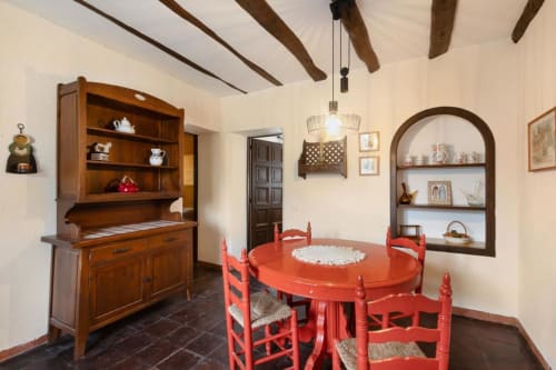 Comedor rústico de Masia Rural Ca l'Eloi Janet Barcelona con sillas rojas, vigas de madera y decoración tradicional