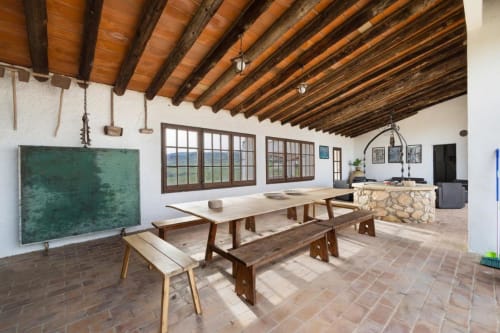 Comedor rústico con vigas de madera, mesas largas y pizarra verde en Masia Rural Ca l'Eloi Janet cerca de Barcelona