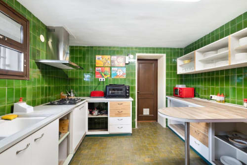 Cocina con azulejos verde brillante, encimeras de madera, electrodomésticos rojos y estantes abiertos en Masía Rural Ca l'Eloi Janet, Barcelona