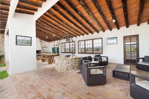 Spacious villa living area at Masia Rural Ca l'Eloi Janet near Barcelona with exposed wooden beams, stone fireplace, black