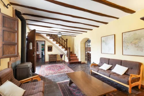 Spacious villa living room at Masia Rural Ca l'Eloi Janet near Barcelona with wooden beams, fireplace, comfortable seating,