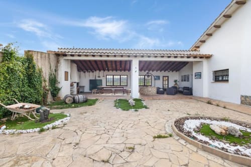 Patio rústico de la masía Ca l'Eloi Janet cerca de Barcelona con terraza de piedra, áreas techadas y jardines