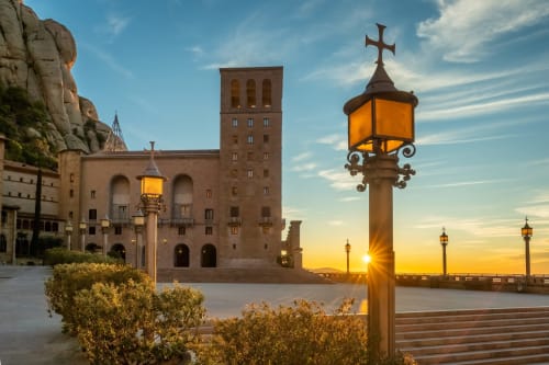 Monasterio de Montserrat al atardecer con cruz iluminada y arquitectura de piedra cerca de Barcelona