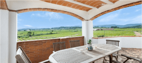 Terraza cubierta con mesa de comedor con vistas a los viñedos de Masia Rural Ca l'Eloi Janet, Barcelona