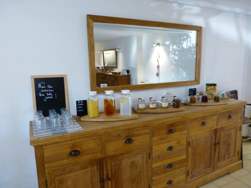 Frühstücksbuffet der Villa Thébaïde mit Holzschrank, Getränken und Spiegel in Laudun L'Ardoise