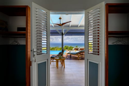 Les portes ouvertes révèlent une terrasse avec vue sur mer, piscine et mobilier de détente à Chez Marie et Philippe, Marie-Galante
