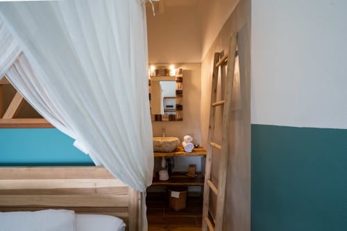Chambre avec lit à baldaquin et voilages blancs donnant sur la salle de bains attenante chez Marie et Philippe, Marie-Galante