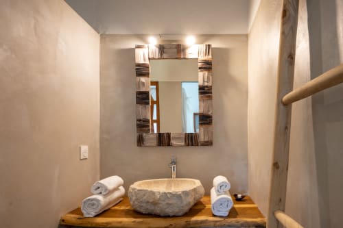 Lavabo en pierre rustique avec serviettes roulées sur plan de travail en bois à Chez Marie et Philippe, salle de bain de la maison d'hôtes de Marie-Galante