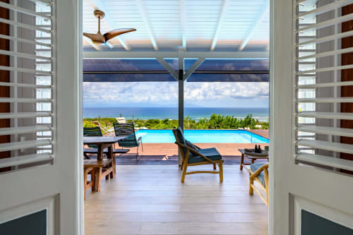Terrasse de Chez Marie et Philippe à Marie-Galante avec vue sur mer, piscine privée, chaises longues et horizon océanique.