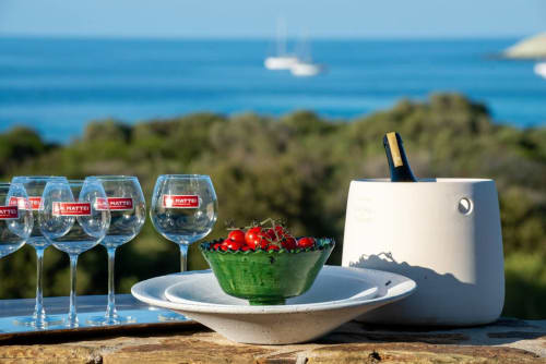 Verres de vin et tomates fraîches sur la terrasse bord de mer de la villa La Conciergerie du Cap Corse avec vue sur la mer Méditerranée