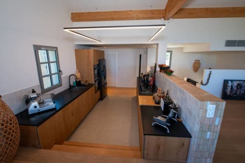 Cuisine moderne de la Villa Camille à La Conciergerie du Cap Corse, Centuri avec poutres en bois, plans de travail noirs et inox