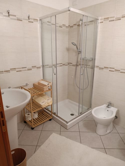 Modern bathroom at La Tour B&B in Oyace with corner shower, bidet, pedestal sink and wooden storage shelf