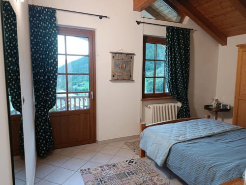 Gianluca bedroom at La Tour B&B in Oyace with mountain views, double bed, dark patterned curtains, and wooden beams