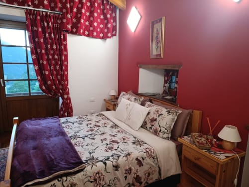 Camera Orsola presso La Tour B&B a Oyace con biancheria floreale, pareti rosse, tende a fiocchi di neve e vista montagna
