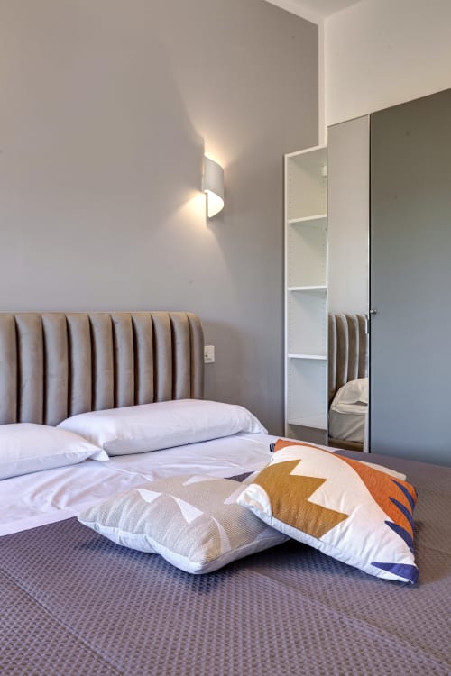 Modern double bedroom at Palazzo Belvedere with upholstered headboard, mirrored wardrobe, and contemporary furnishings in