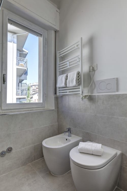 Modern bathroom at Palazzo Belvedere with bidet, sink, heated towel rack, and window overlooking Chianciano Terme