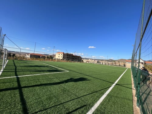 Modern soccer field at Riad Gold Hôtel in Azrou with green artificial turf, white lines, and surrounding mountains under