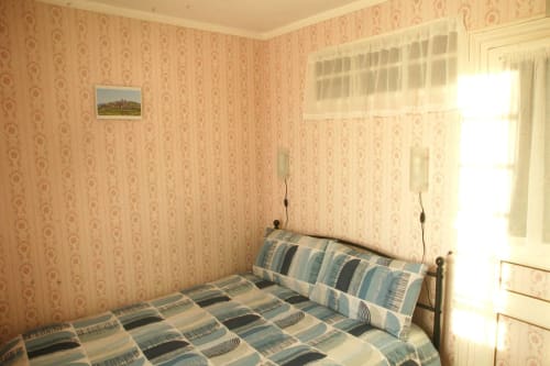 Cozy bedroom at Les Gîtes de l'Impériale in Sermizelles with patterned wallpaper, striped bedding, and natural light from