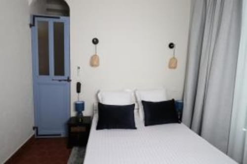 Chambre double moderne à l'Hôtel Villa Roseraie à Vence avec literie blanche, oreillers noirs, luminaires suspendus en bois et bleu