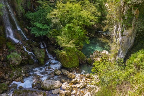 Scenic gorge with turquoise stream and waterfalls surrounded by lush greenery in Vence, France