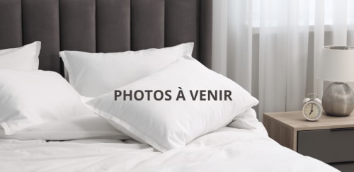 Chambre moderne de la Villa Roseraie à Vence avec oreillers blancs, tête de lit foncée et table de nuit avec réveil