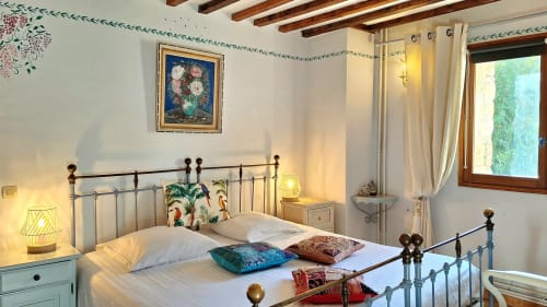 Lavender room at La Bergerie Du Moulin B&B in Taradeau, France, featuring an iron bed with colorful pillows and warm lighting