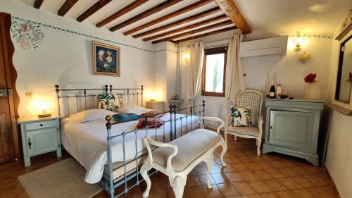 Lavender room at La Bergerie Du Moulin in Taradeau with metal bed frame, white linens, turquoise nightstands, and exposed
