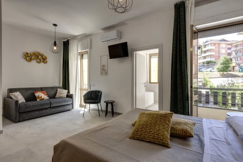 Modern hotel room at Palazzo Belvedere with bed, sofa, balcony overlooking Chianciano Terme, TV, and elegant furnishings