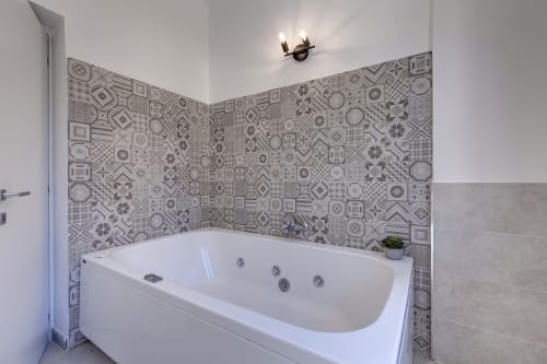 Modern bathroom with white jacuzzi tub and decorative patterned tile walls at Palazzo Belvedere hotel in Chianciano Terme,