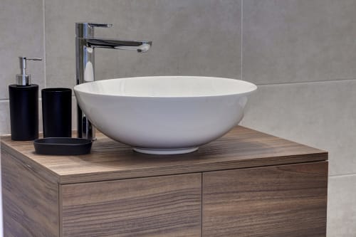 Modern white vessel sink with chrome faucet on wooden vanity at Palazzo Belvedere hotel bathroom in Chianciano Terme