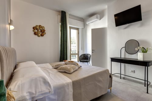 Modern double bedroom at Palazzo Belvedere with balcony view, flat-screen TV, desk, and contemporary furnishings in