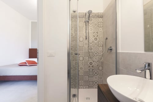 Modern bathroom at Palazzo Belvedere with patterned tile shower, white vessel sink, and glass enclosure in Chianciano Terme