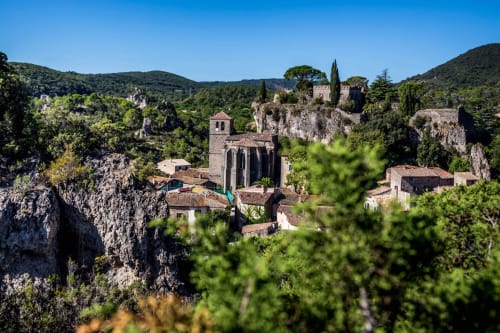 Village médiéval avec église en pierre et ruines de château nichés dans des collines verdoyantes près de Plaissan, France