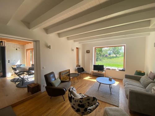 Modern villa lounge with exposed beams, green garden views, furniture, and natural light from large windows at Locavilla,