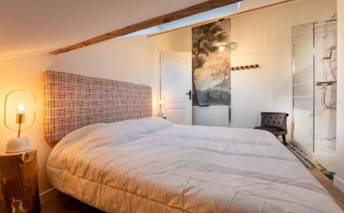 Modern bedroom at Maison de Sophie B&B in Rencurel with white bedding, textured headboard, and ensuite shower.