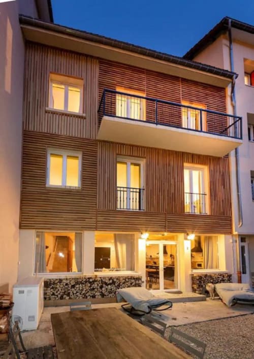 Maison de Sophie, gîte à Rencurel, façade en bois moderne et entrée illuminée au coucher du soleil