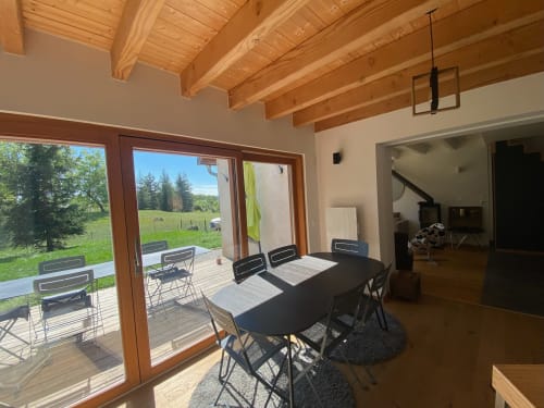 Locavilla villa dining area with wooden beams, table, and glass doors opening to terrace with mountain views near Colombes
