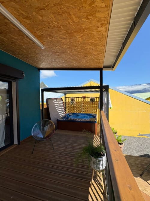Terrasse vue montagne de la villa Au pied des Sources à Cilaos avec terrasse bois, coins ombragés et architecture jaune
