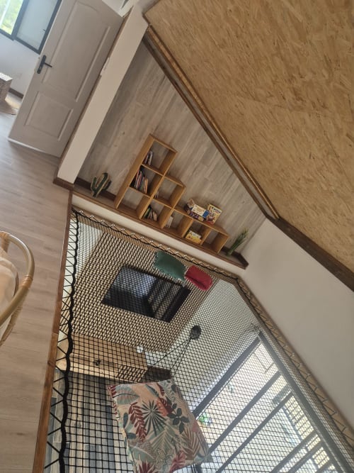 Chambre de la villa Au pied des Sources à Cilaos avec mobilier en bois et vue sur les montagnes par les fenêtres grillagées