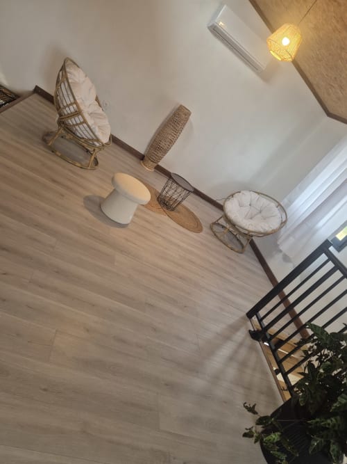 Salon moderne de la villa Au pied des Sources avec fauteuils en rotin tressé, luminaires suspendus et vue sur les montagnes de Cilaos