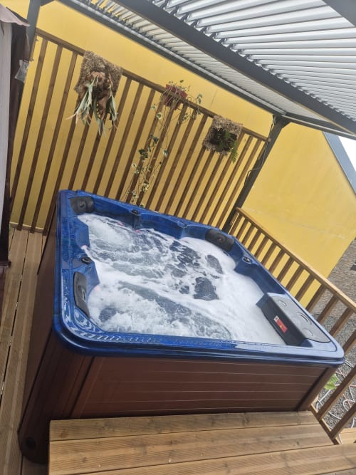 Bain à remous bleu avec eau bouillonnante sur terrasse en bois à la villa Au pied des Sources à Cilaos, vue sur les montagnes