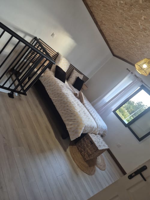 Chambre de villa moderne à Au pied des Sources à Cilaos avec vue sur les montagnes, lit en métal noir et lumière naturelle